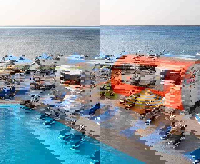 Poolside area with sun loungers, and a snack bar and the sea in the background