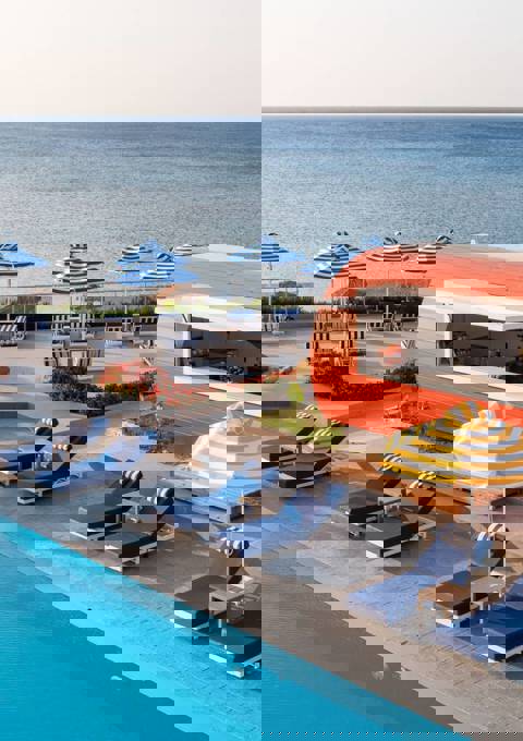 Poolside area with sun loungers, and a snack bar and the sea in the background