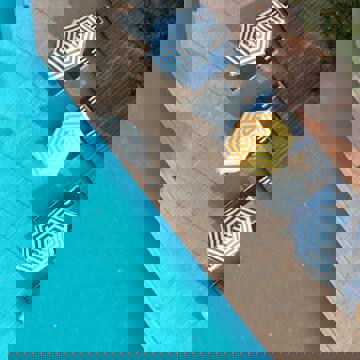 Aerial view of poolside loungers with striped umbrellas next to a swimming pool