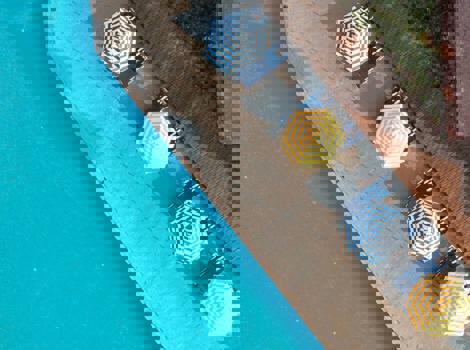 Aerial view of poolside loungers with striped umbrellas next to a swimming pool