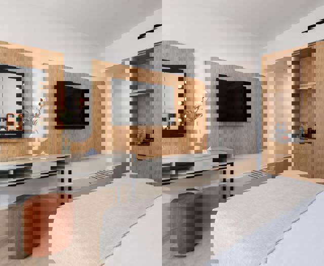 Hotel room with bed, wall-mounted TV, vanity with lighted mirror, wooden wardrobe and orange stool
