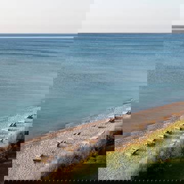 Sunny beach with rows of wooden sun loungers facing the sea