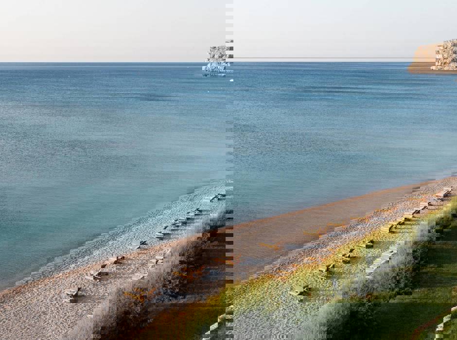 Sunny beach with rows of wooden sun loungers facing the sea