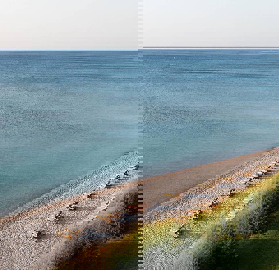 Sunny beach with rows of wooden sun loungers facing the sea