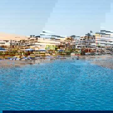 Large pool with striped umbrellas, blue loungers, and hotel buildings in the background