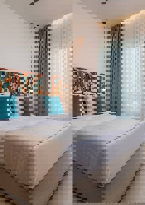 Premium Deluxe hotel room with large bed, patterned headboard, balcony and sea view through glass doors