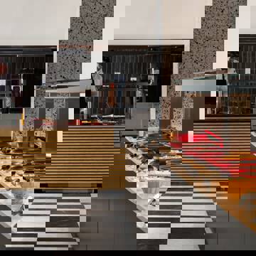 Buffet station with red serving trays, baskets of bread and chef preparing food behind striped counter
